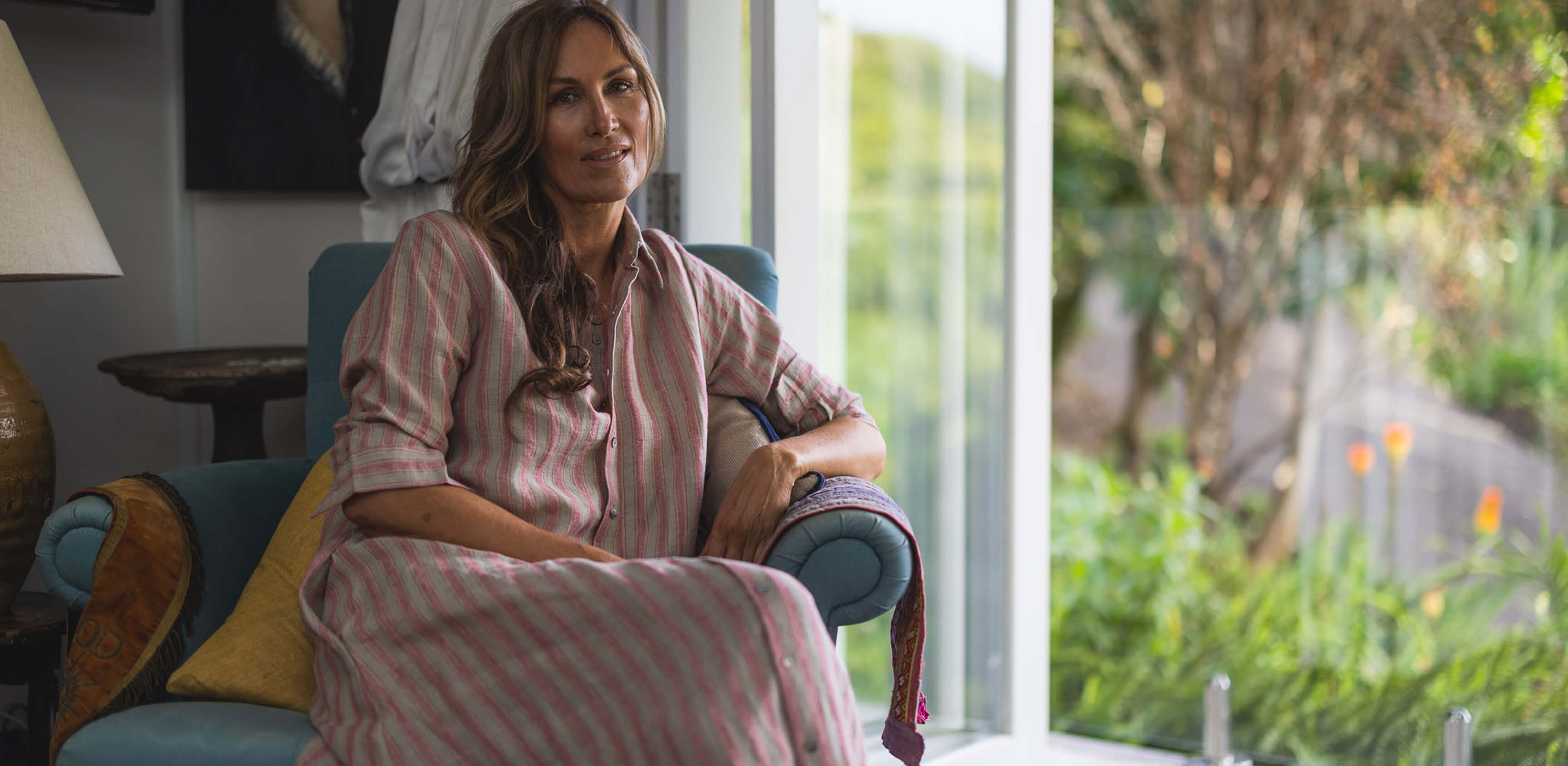 Women wearing The Tailor and his Lover dress sitting in her lounge with a garden background