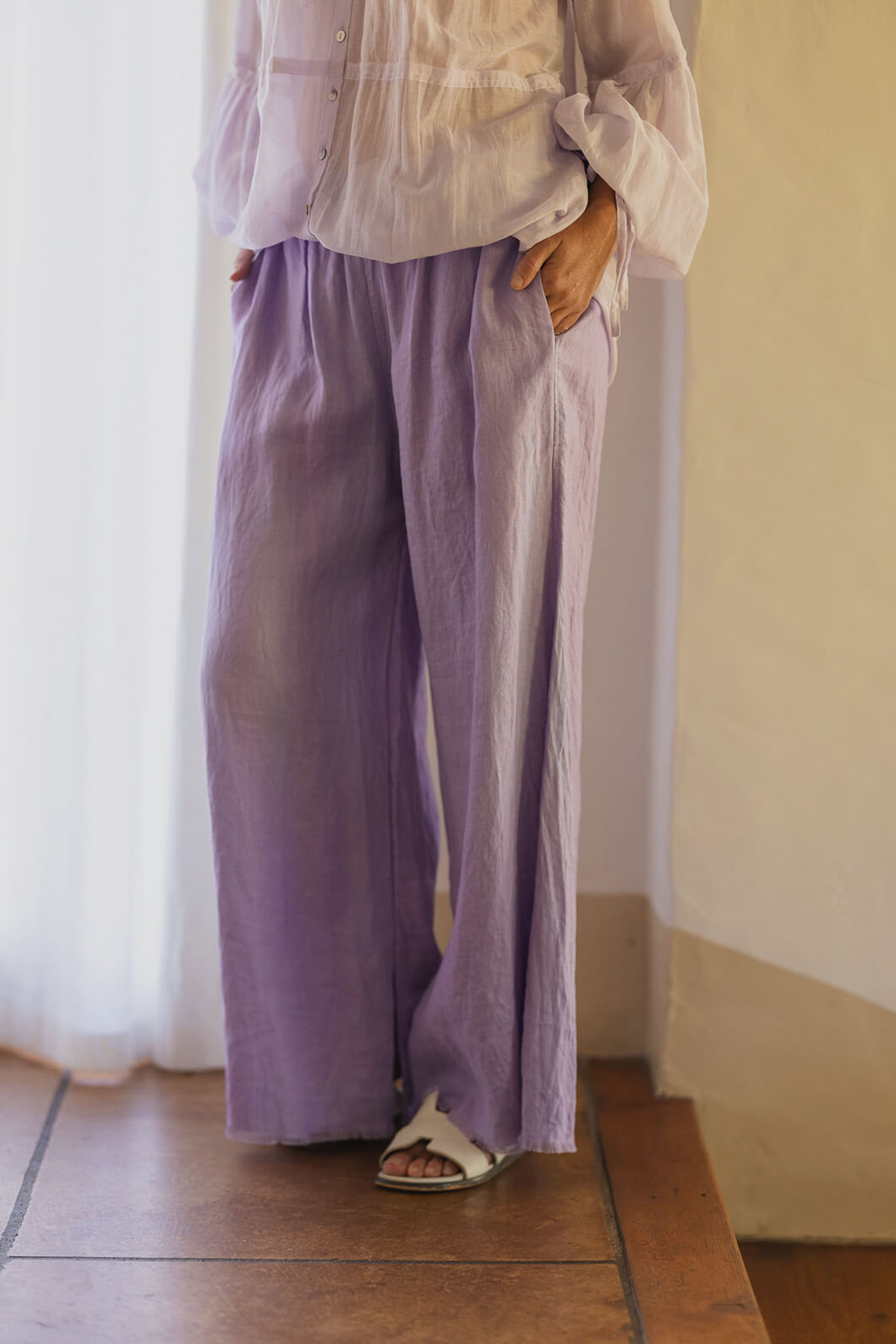 Women wearing lazy linen in lilac with white curtain and steps in background